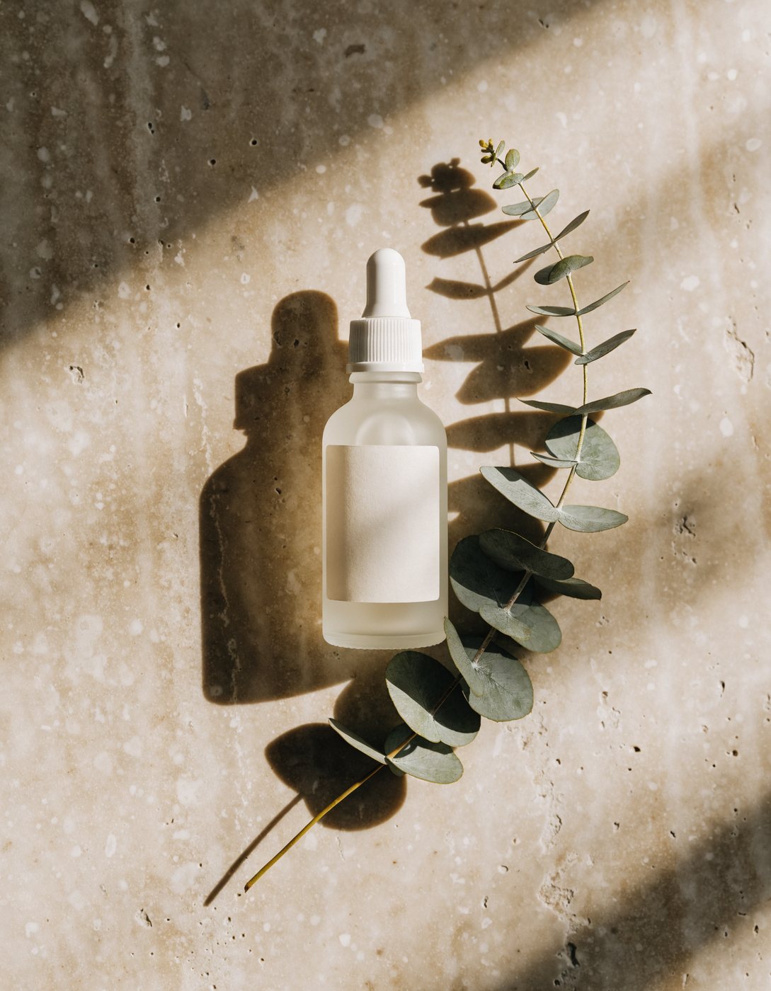 Unbranded serum bottle flat lay with eucalyptus