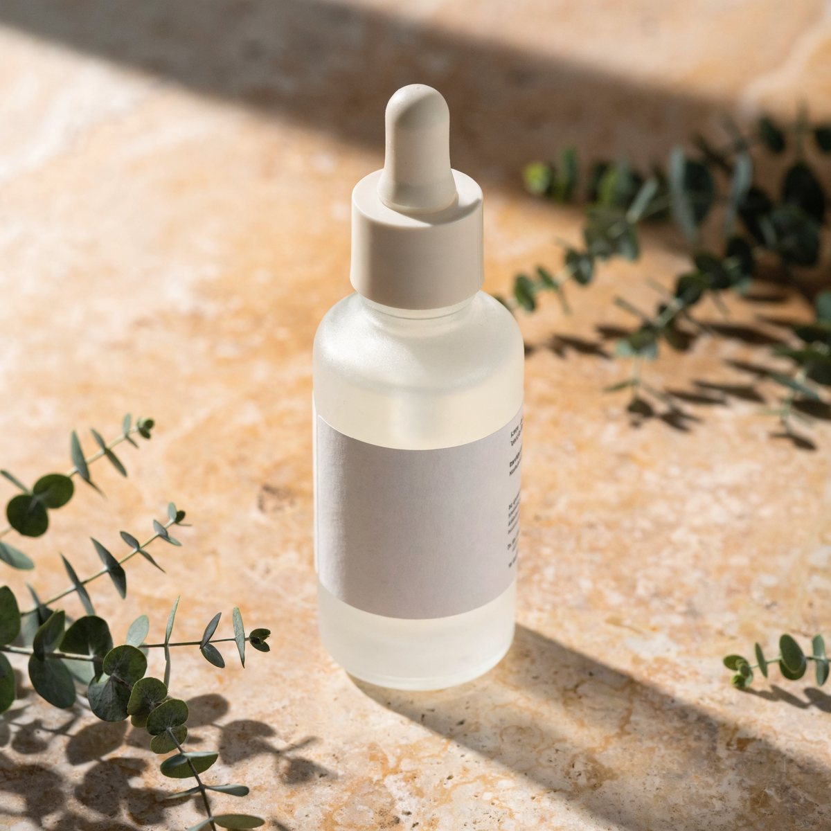 Serum bottle styled for spring with green eucalyptus